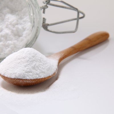 Close-Up Of Baking Soda In Wooden Spoon And Jar On White Background
