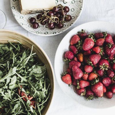 Cheese, bread, fruits and arugula on a table