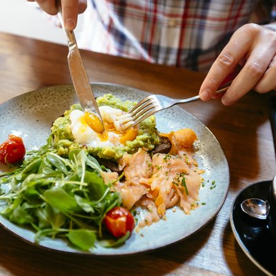 Eating choline foods like avocado toast with egg, salmon and arugula salad for brunch at the restaurant