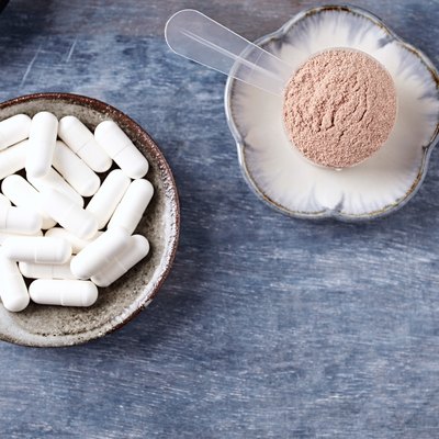 Creatine capsules, Scoop of Whey Protein and plates. Nutrition for bodybuilding. Fitness supplements on rustic wooden background. Directly Above. Copy space