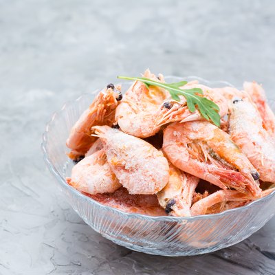 Group of frozen shrimp and a leaf of arugula in a glass bowl