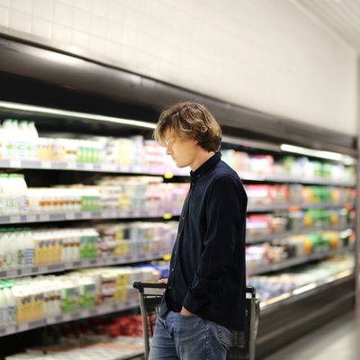 Teenager shopping in supermarket, reading product information