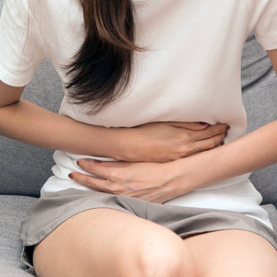 The woman holds her stomach with both hands. Stomach upset or pain during menstruation.