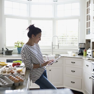 Woman using myWW app on digital tablet to prepare a recipe in kitchen