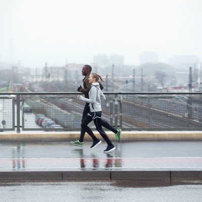 two friends jogging across urban street bridge