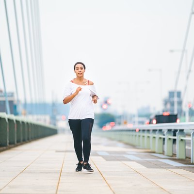 Mixed race woman running in city on cloudy bad weather day