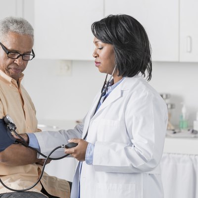 African American doctor checking senior man's blood pressure
