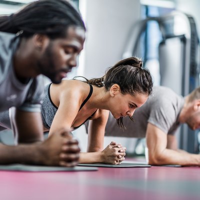 Group of athletes in a plank position at health club.