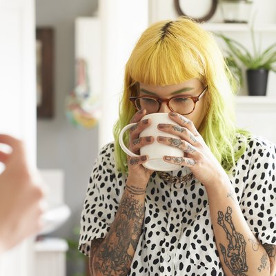 Young hipster woman drinking from a mug in her kitchen