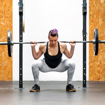 Young girl doing a back squat with a barbell