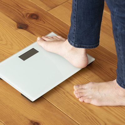View of a person's feet stepping onto a bathroom scale