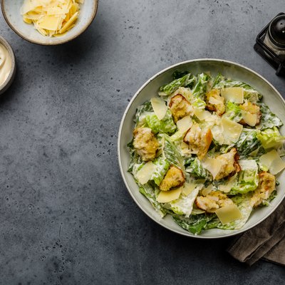 Caesar salad with croutons and parmesan cheese on concrete background copy space