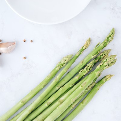 Fresh green asparagus with garlic and white peppercorns on marble table