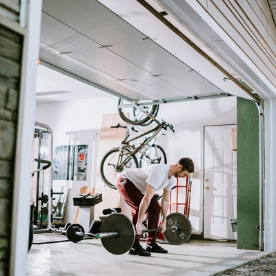 Man lifting barbell to build muscle in garage