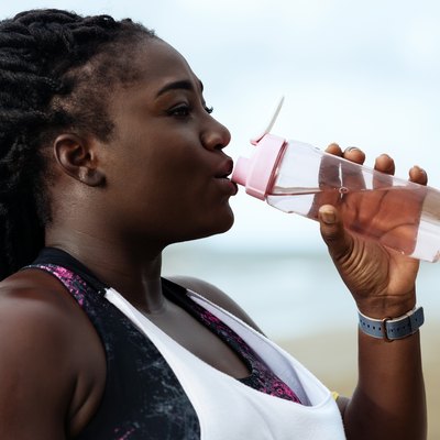 Black woman wearing workout clothes and drinking water