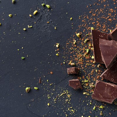 Broken chocolate pieces and cocoa powder on black background