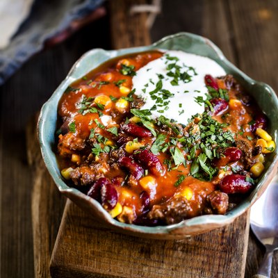 Chili con carne with kidney beans and corn, sour cream, parsley, tortilla bread