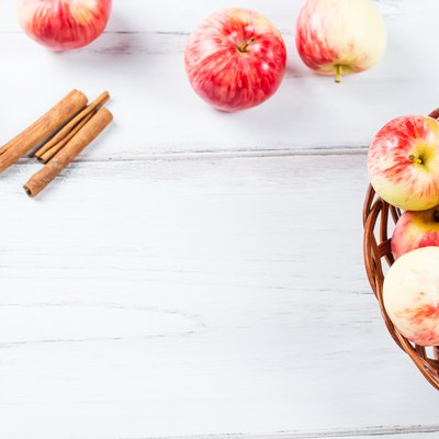 autumn mood composition with red apples in wicker basket and yellow leaves