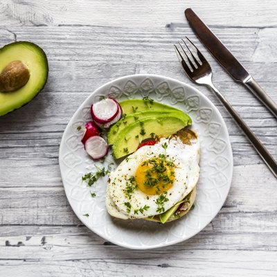 Toast with with fried egg, avocado, red radish, tomato and cress