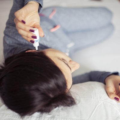 Woman using ear drops at home