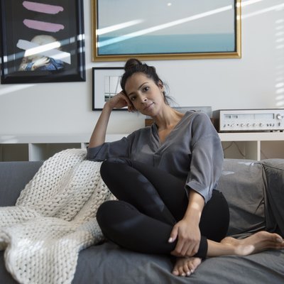 Portrait confident Latina woman relaxing on living room sofa