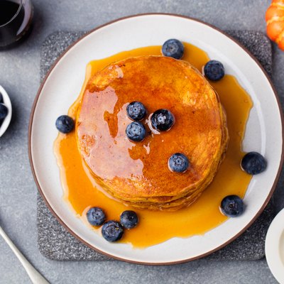 Pumpkin pancakes with maple syrup and blueberries on a plate.