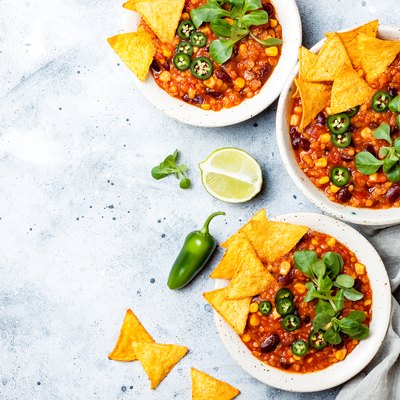 Vegetarian chili con carne with lentils, beans, nachos, lime, jalapeno. Mexican traditional dish