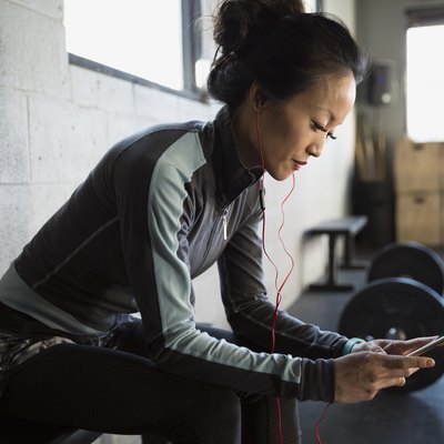 Woman with headphones using cellphone at gym