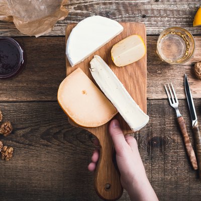 Close up hand holding cutting board with cheese