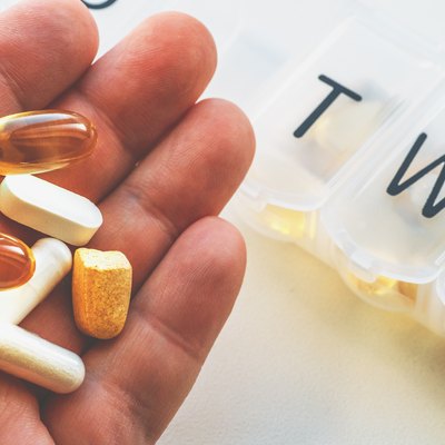 Pill box or organizer with drugs, male hand shows medications, Daily vitamins