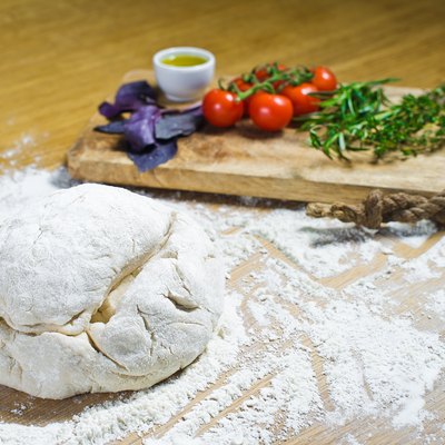 Pizza dough with cutting board with veggies