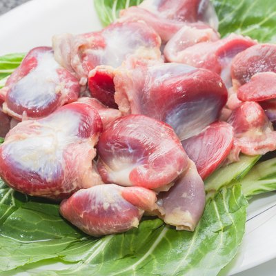 Fresh chicken gizzards and gizzards are placed in white porcelain saucers