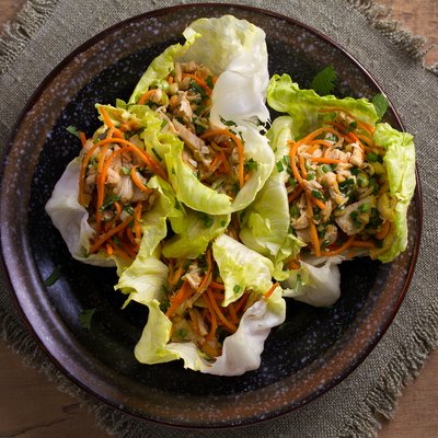 Lettuce wraps with chicken, carrot, peanuts and scallion. Stuffed iceberg lettuce leaves with chicken