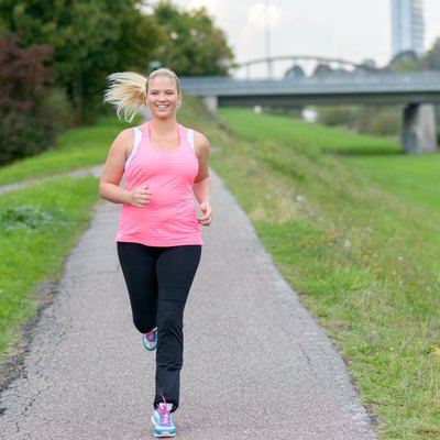 Blonde smiling woman running along river