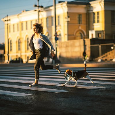 Energetic woman running on pedestrian way with dog in city