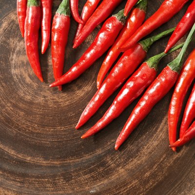 Red hot chili peppers on brown clay flat plate. Copy space. Top view. Food background.