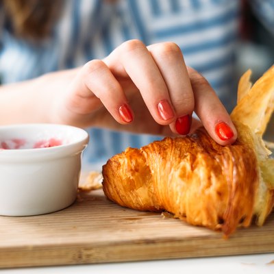 Woman eating croissant, which is one of the trans fat foods