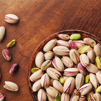 Bowl of pistachio nuts on wooden rustic table top view. Healthy food and snack. Vintage.