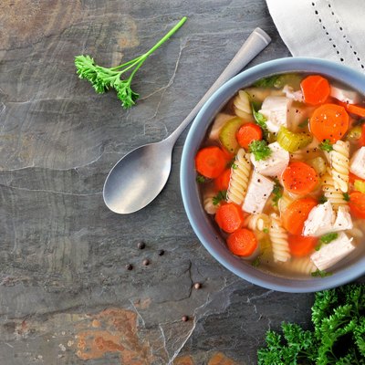 Homemade chicken noodle soup with vegetables, above on dark slate