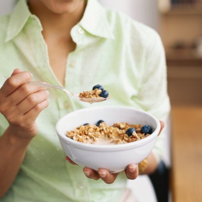 Woman holding bowl of cereal, mid section, close-up