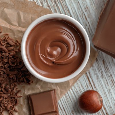 Bowl with tasty melted chocolate on wooden background