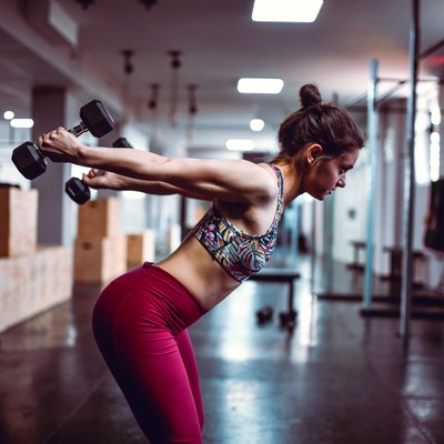 Female Doing Dumbbell Exercises In Gym