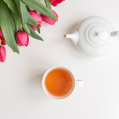 Red tulips, white teapot and cup from above