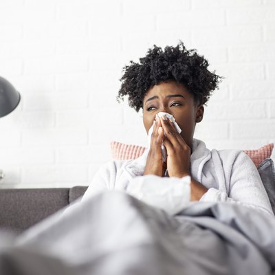 Woman lying in bed with virus and high temperature