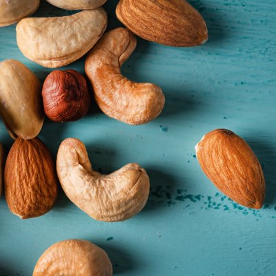 Assortment of nuts in wooden bowl on blue wooden table