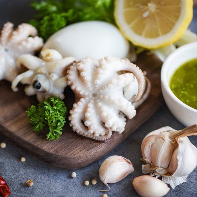 Squid salad spices lemon garlic chili sauce on wooden cutting board background - cooked food squids octopus or cuttlefish at seafood restaurant