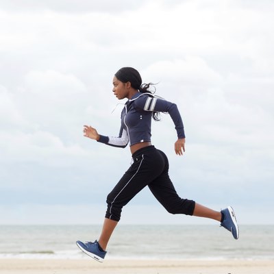 side portrait of african american woman running by the beach
