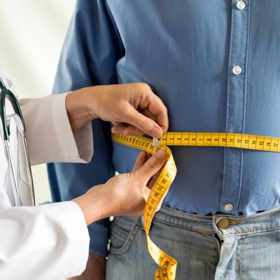 A doctor measuring a man's waist to determine if his body fat percentage is considered obese
