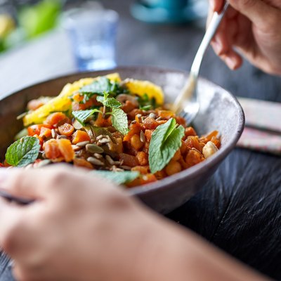 Healthy person eating organic chickpea salad from bowl with fork at rustic bohemian restaurant