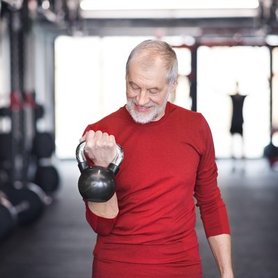 Senior man exercising with kettlebell in gym